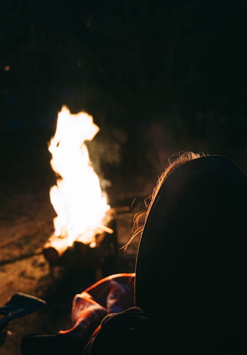 Person Sitting by Bonfire at Night