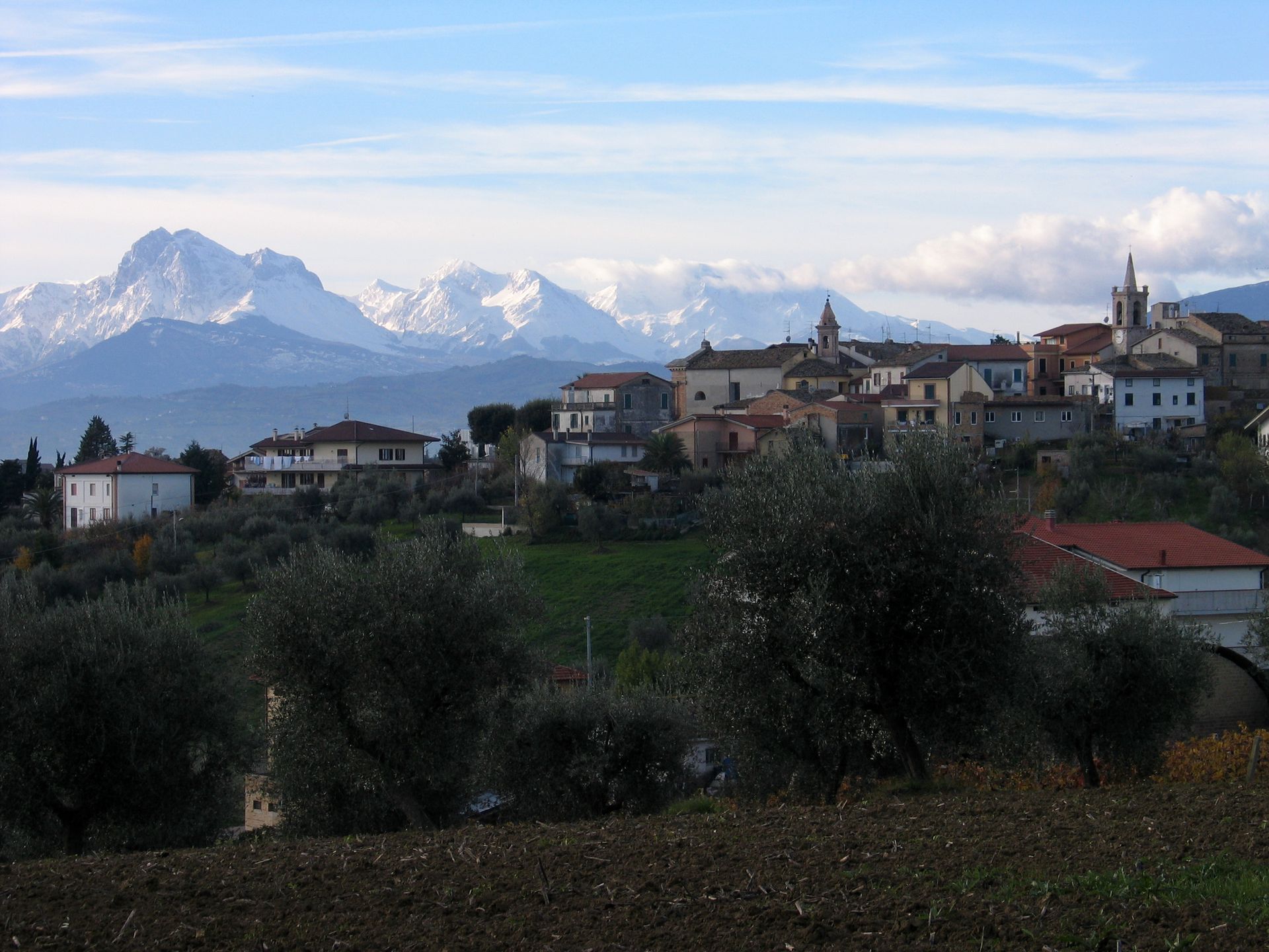 Scenic view of an Italian village nestled against majestic snow-capped mountains.