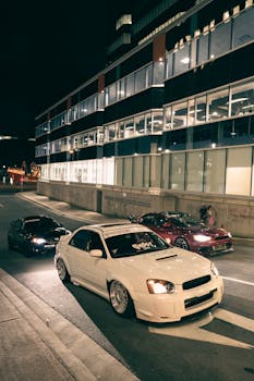 Modern cars parked on an urban street at night, showcasing luxury and style.