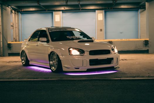 A white car with purple lights in the parking lot