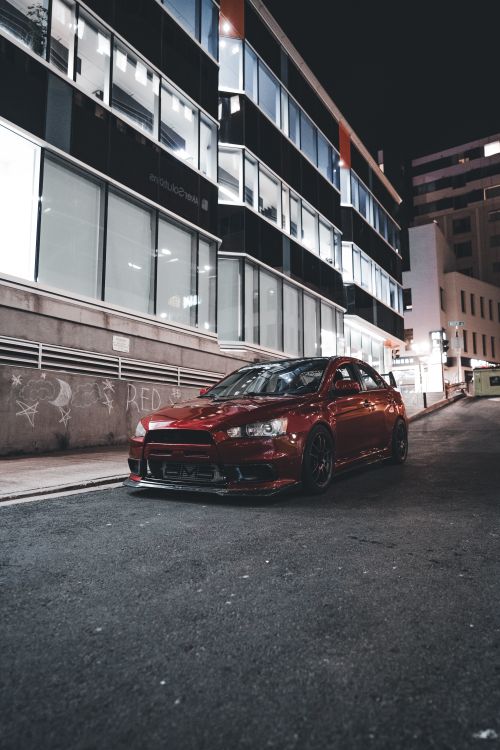A red car parked on the street at night · Free Stock Photo