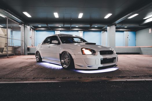 A white car parked in a garage with lights on
