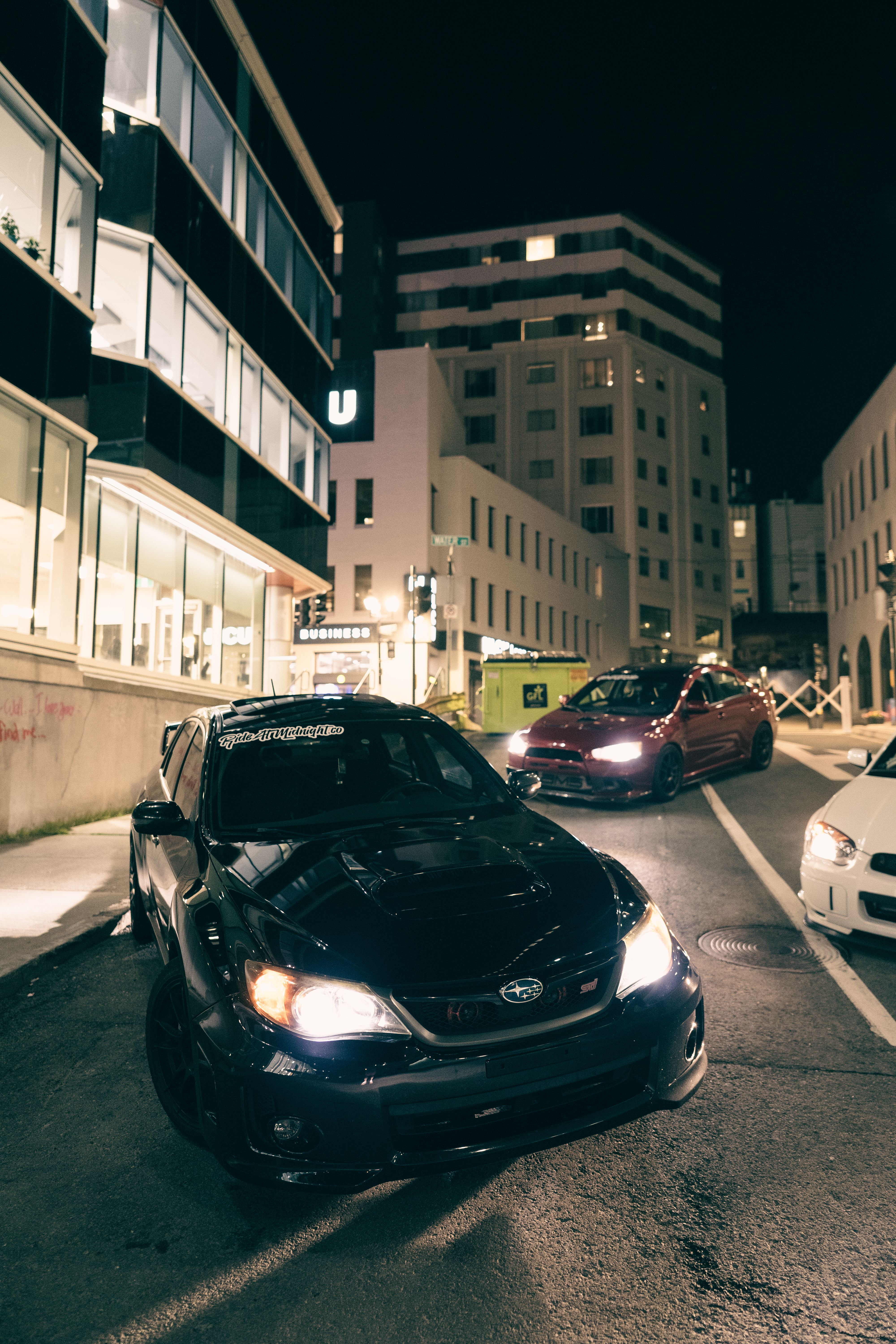 A sleek, modern car on a lit urban street at night, capturing the essence of night driving.