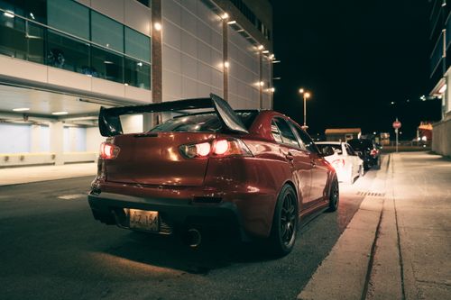 Free A vibrant red sports car parked in an urban setting at night, showcasing city nightlife. Stock Photo