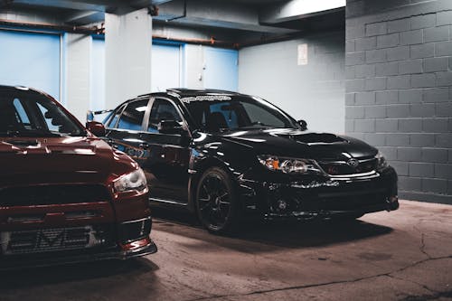 Two cars parked in a garage with a black car