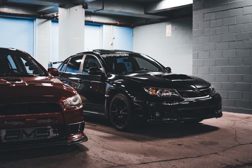 Free Two sports cars stylishly parked in an urban garage, showcasing modern automotive design. Stock Photo
