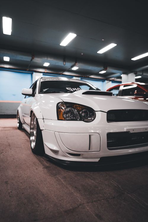Free Stylish white sports car parked in an indoor garage with modern lighting. Stock Photo