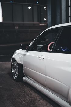 Stylish white car parked in a dimly lit urban area at night, emphasizing luxury and sleek design.