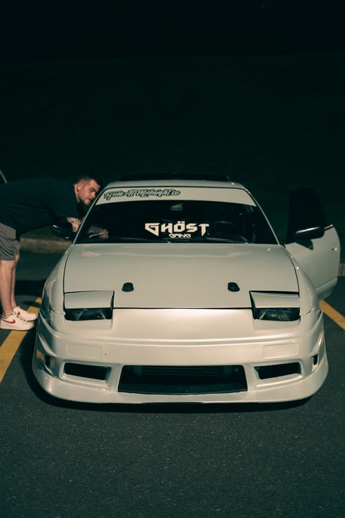 Free Close-up of a white sports car with custom decals in a parking lot at night. Stock Photo