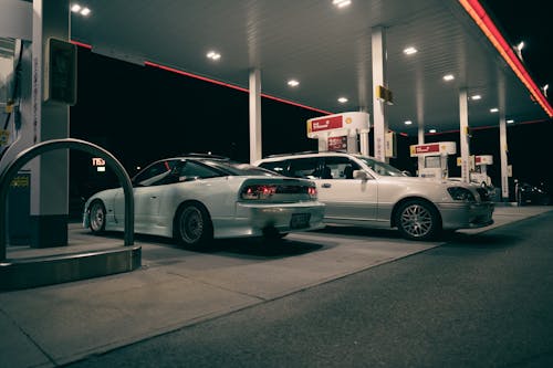 Two cars parked at a gas station at night