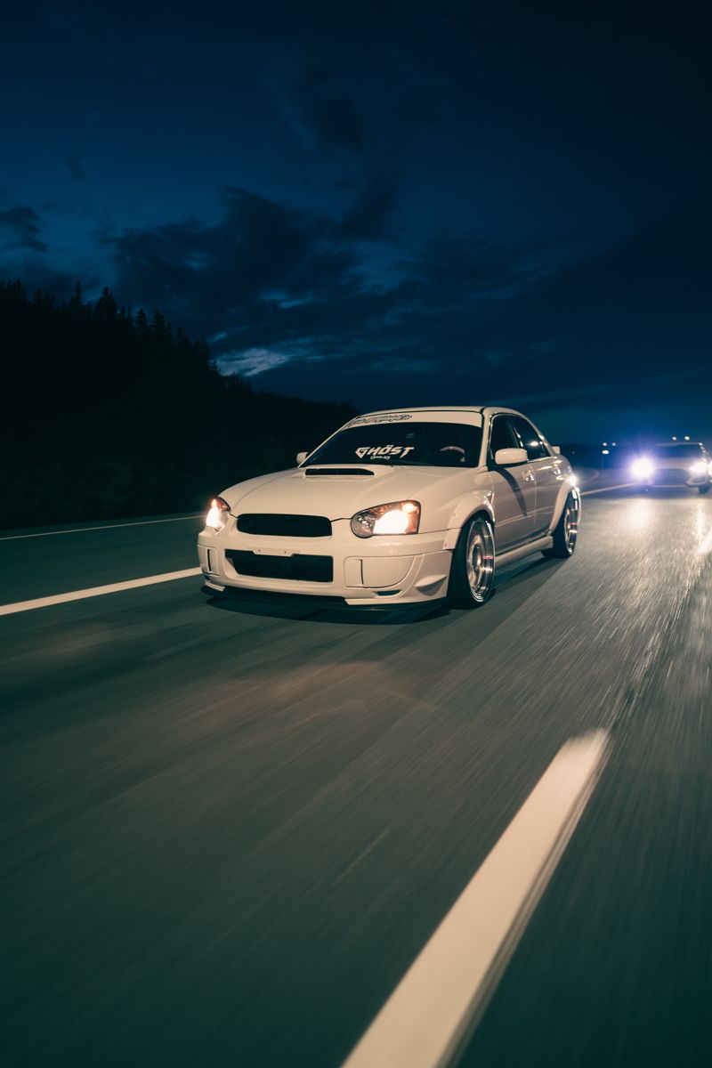 A black car driving down the road at night · Free Stock Photo