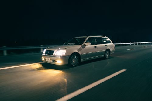 Free A car speeding on an empty highway at night with headlights illuminating the road. Stock Photo