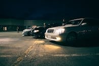A group of cars parked in a parking lot at night