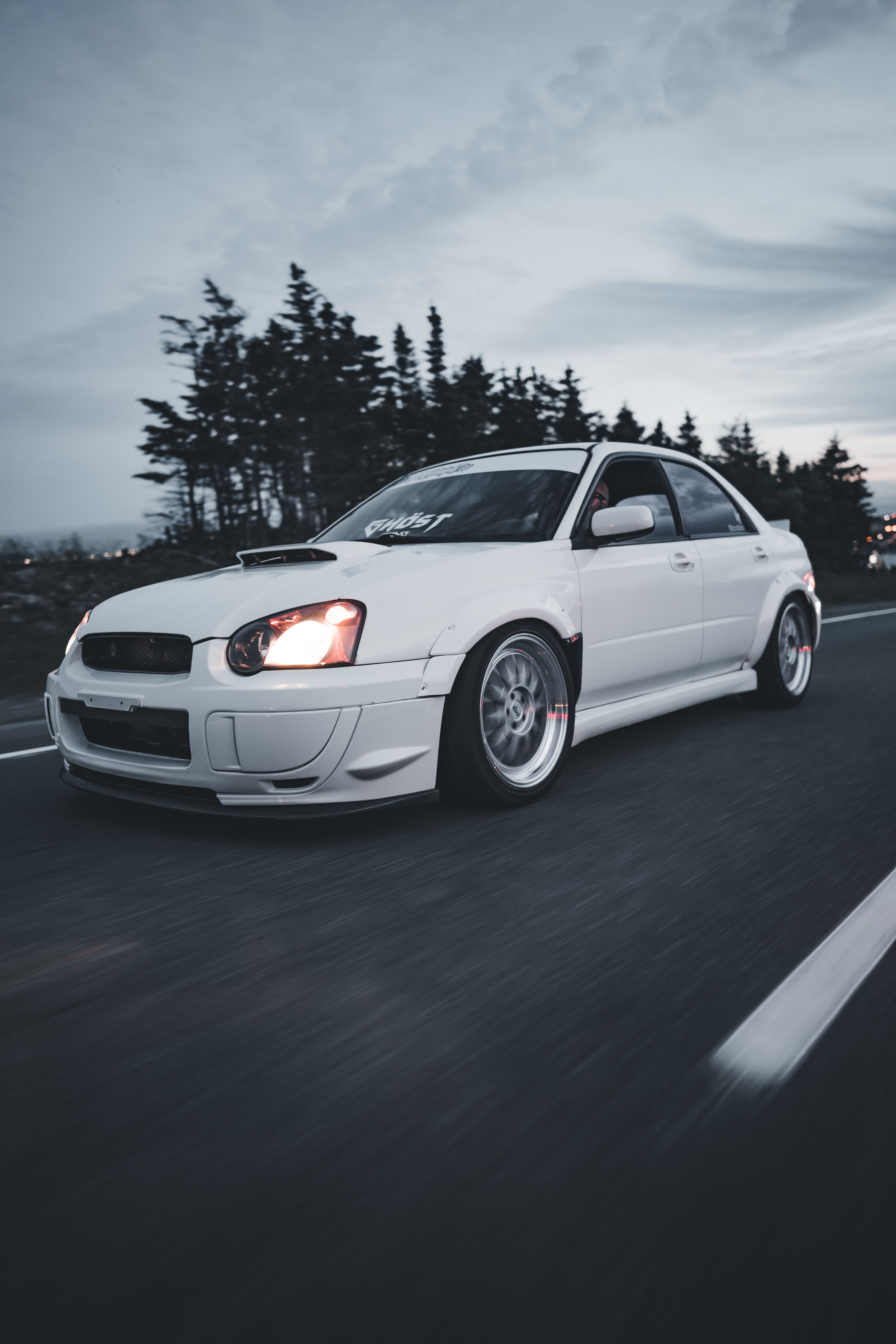 A white car driving down the road · Free Stock Photo