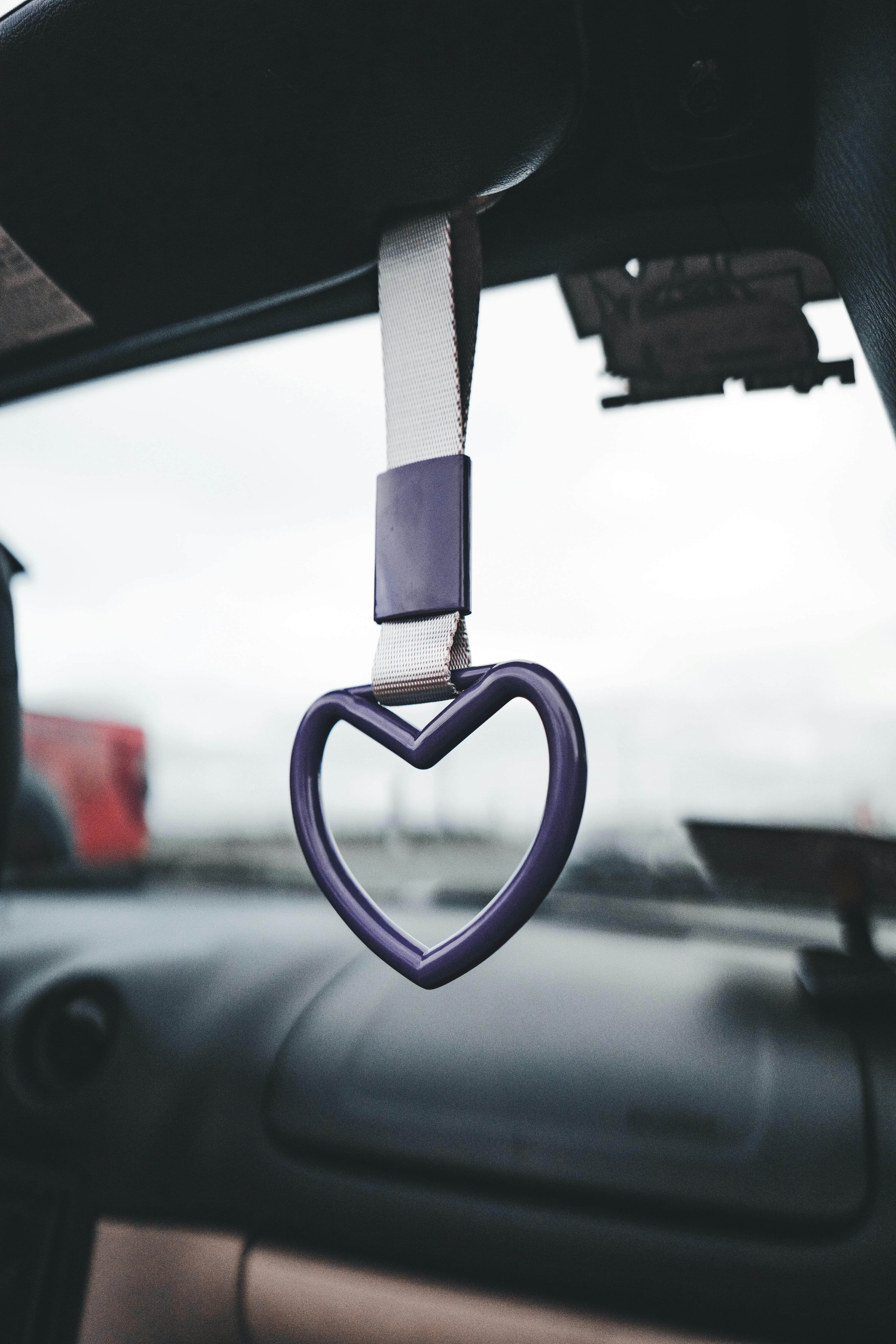 A purple heart shaped car air freshener hanging from the rearview