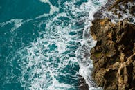 从鸟瞰视角看，海浪撞击岩石海岸线，展现了海洋的自然美景