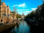 在明净的蓝天下，阿姆斯特丹迷人的运河、建筑和充满活力的城市生活构成了一幅绝美的景色