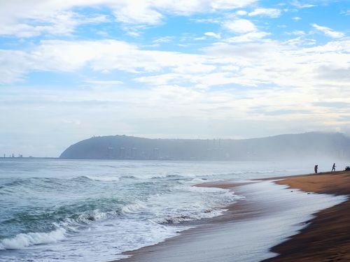 Free A tranquil beachline at dawn with soft waves and distant skyline, perfect for travel and nature themes. Stock Photo