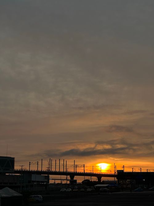 Free Sunset casting vibrant hues over an urban city silhouette with visible structures. Stock Photo