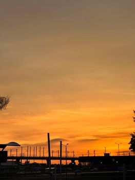 Silhouette of train tracks against a vivid orange sunset sky, highlighting urban travel and tranquility.