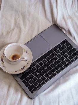 A floral cup of coffee resting on a sleek laptop keyboard, embodying modern work and relaxation.