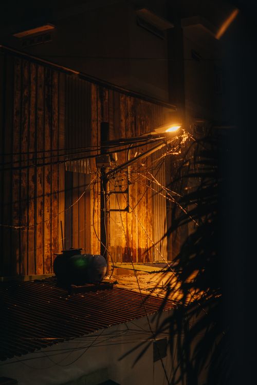 Free A dramatic street scene illuminated by a lone dim street light casting shadows on wooden textures. Stock Photo