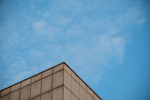 Free Corner of a modern skyscraper set against a bright blue sky, showcasing contemporary architecture. Stock Photo