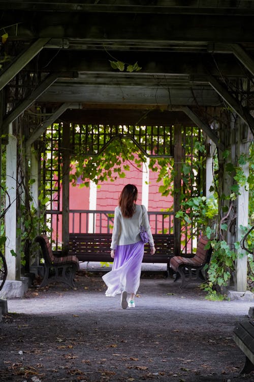 A woman in a long skirt is walking under a covered walkway