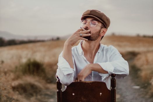 Man smoking in a serene outdoor setting, wearing a cap and glasses.