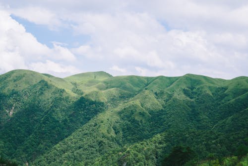 A mountain range with green hills and clouds