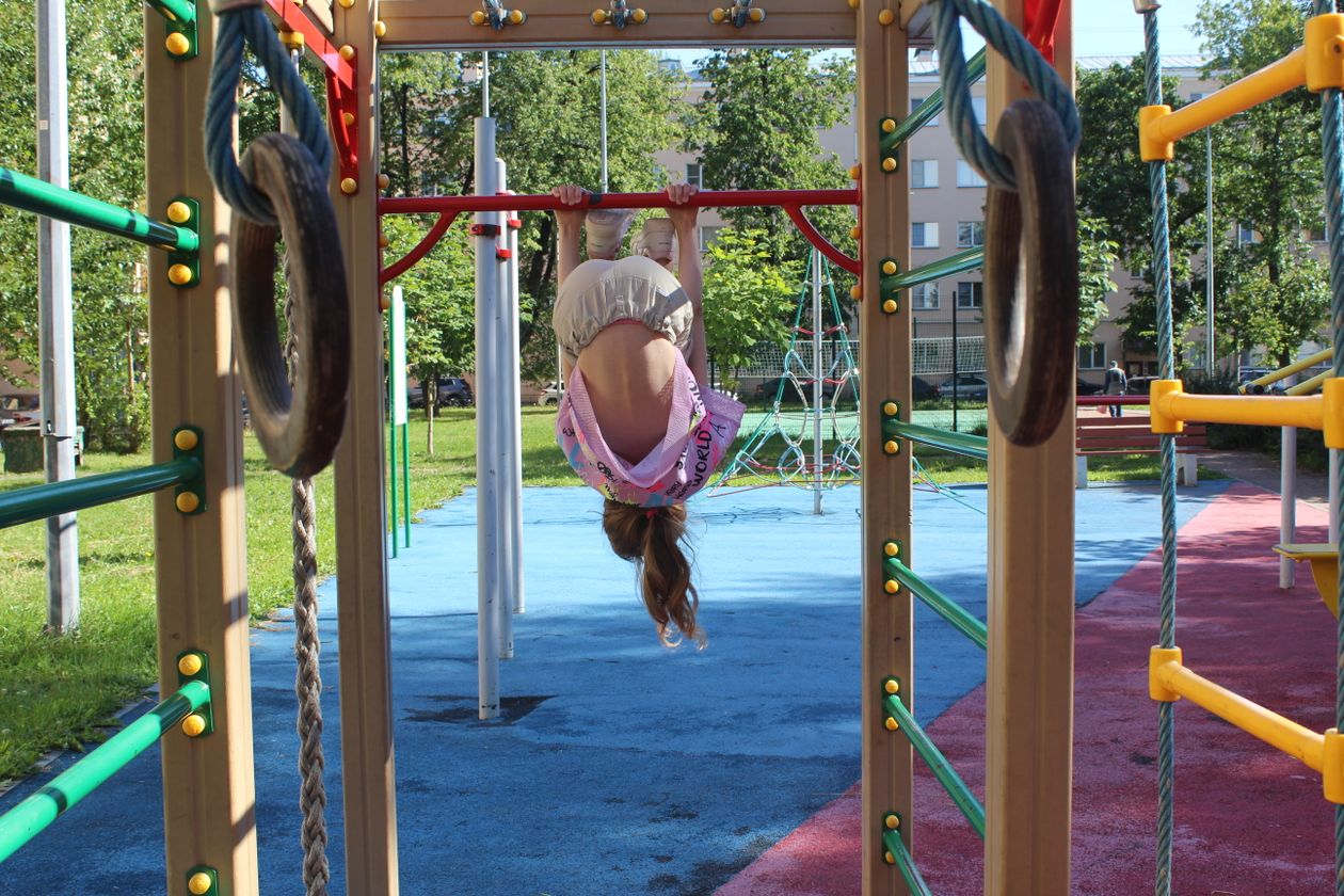 Child hanging upside down from playground climbing equipment