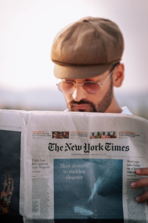 Free A man intently reads a newspaper outdoors on a sunny day, focused and thoughtful. Stock Photo