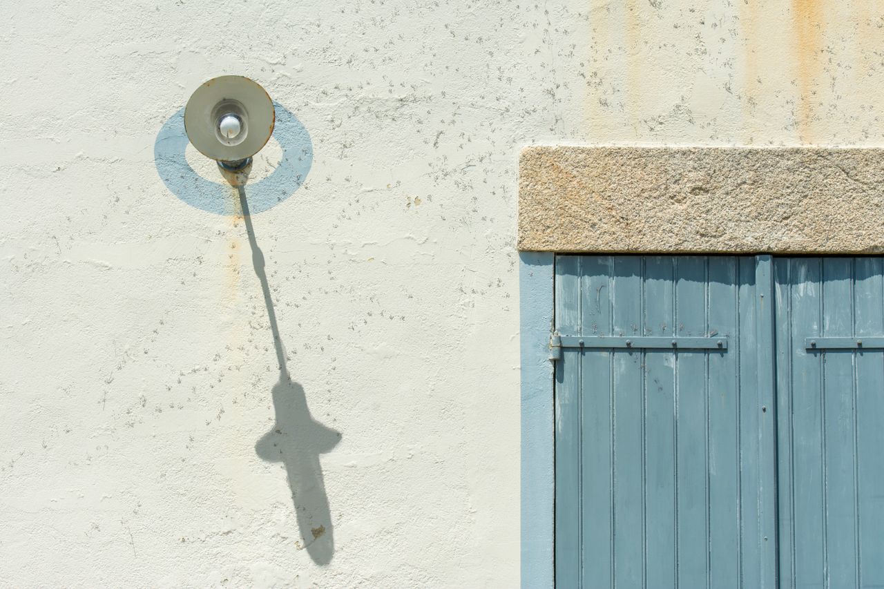 a vintage light fixture casts a shadow on a rustic wall with a blue wo