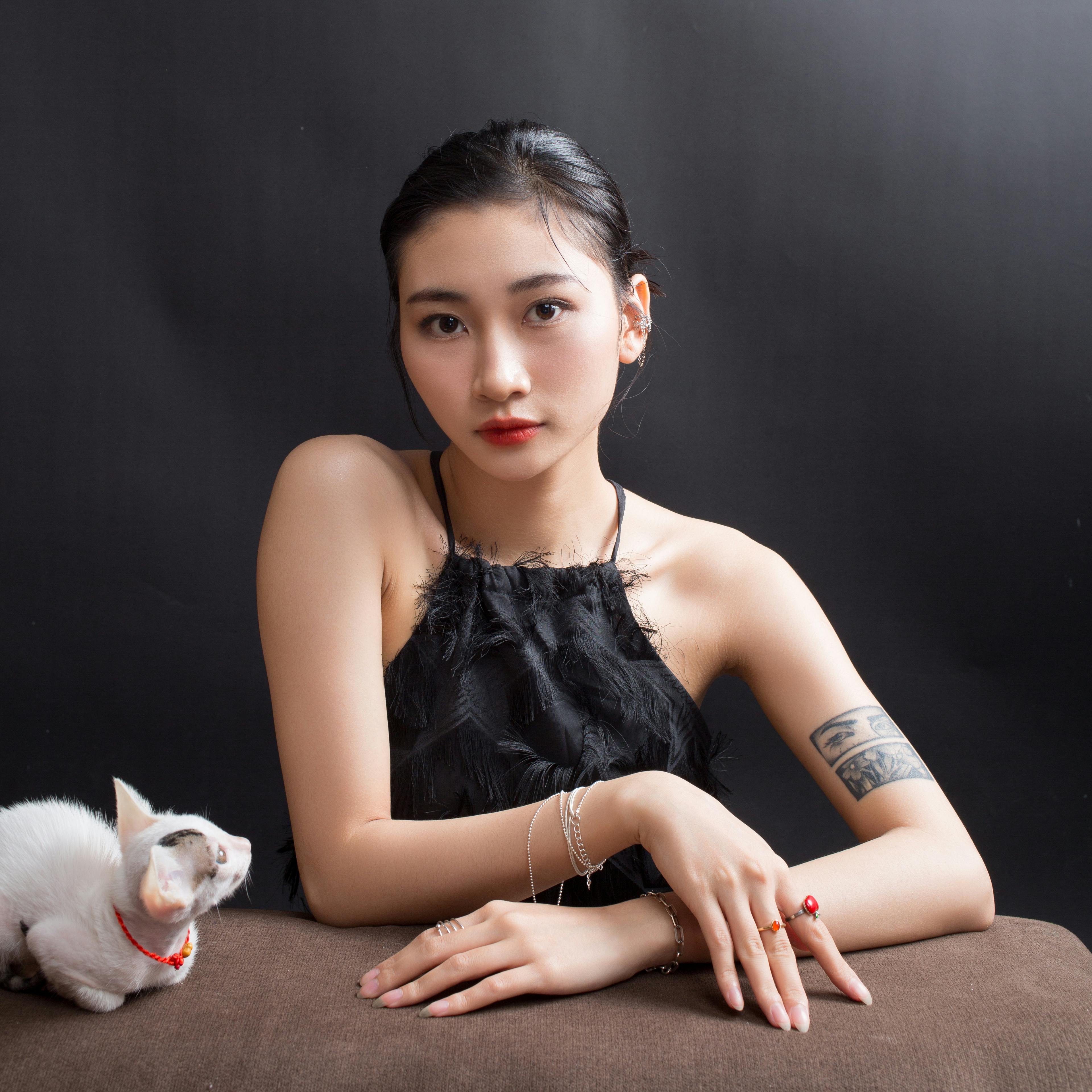 A woman in black dress sitting next to a white cat