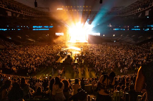 A large crowd at a concert with a stage and lights