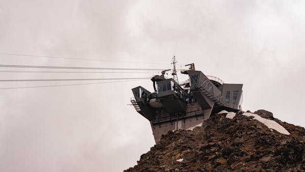 A modern observatory on a rocky mountain top amidst a cloudy sky, showcasing architectural design.
