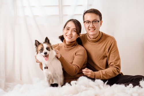 Free A joyful couple and their pet dog indoors, wearing matching outfits. Perfect family photograph. Stock Photo