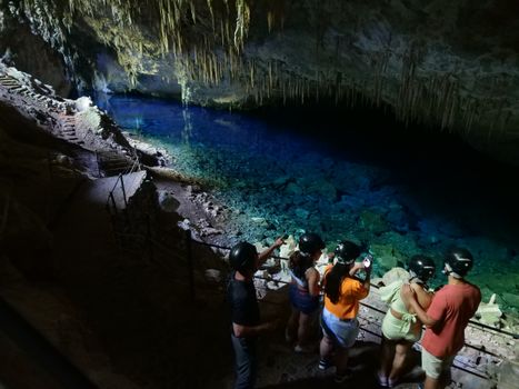 Tourists explore the mesmerizing Gruta do Lago Azul in Bonito, Brazil, showcasing natural beauty and adventure.