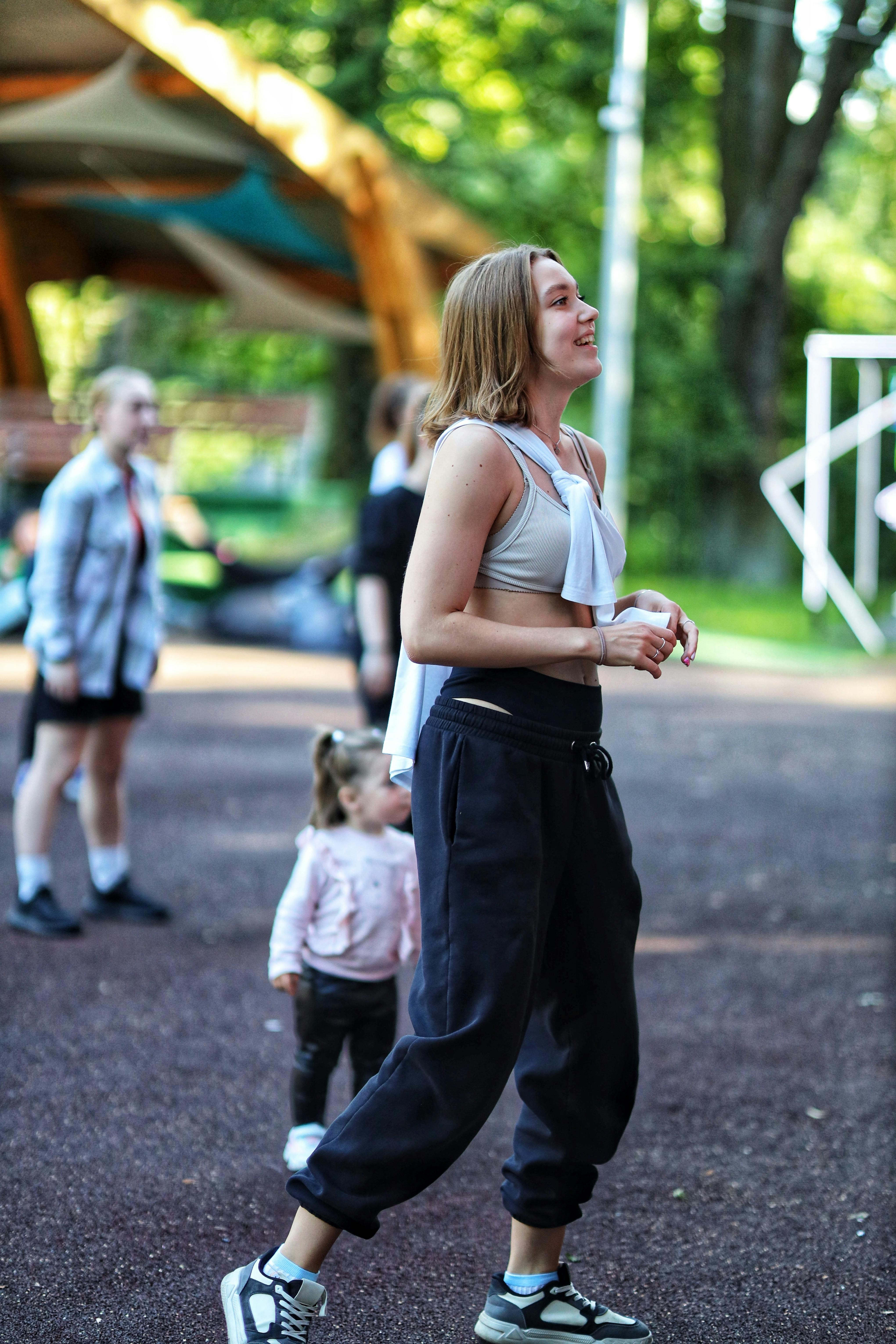 a woman in black pants and a top walking with a child