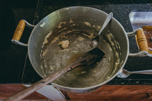 Aerial view of a cooking pot with leftover dough and utensils, highlighting kitchen preparation.