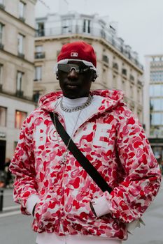 Stylish man in vibrant urban fashion posing on city street.