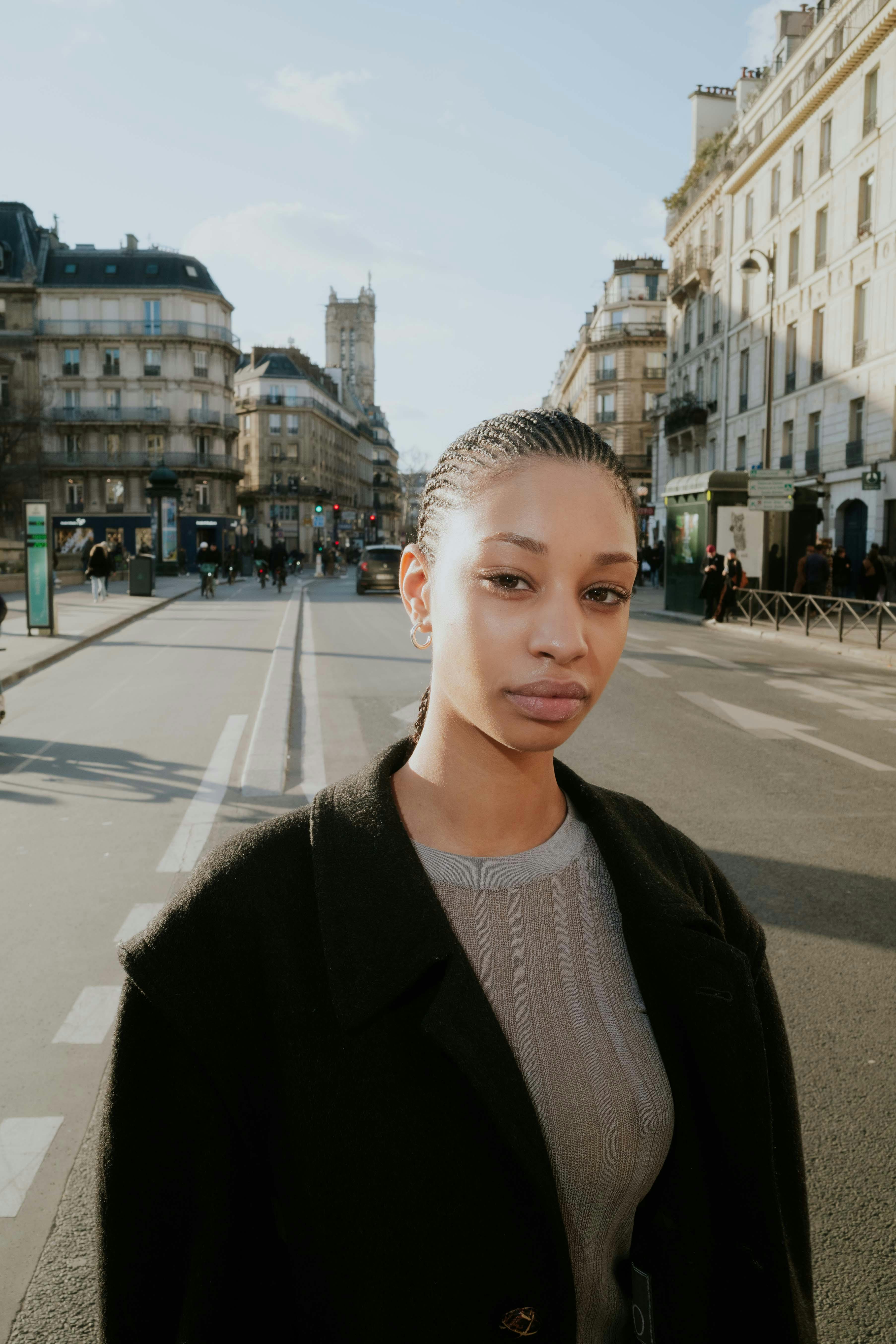 Portrait of a woman in urban city setting, showcasing modern fashion amidst architectural backdrop.