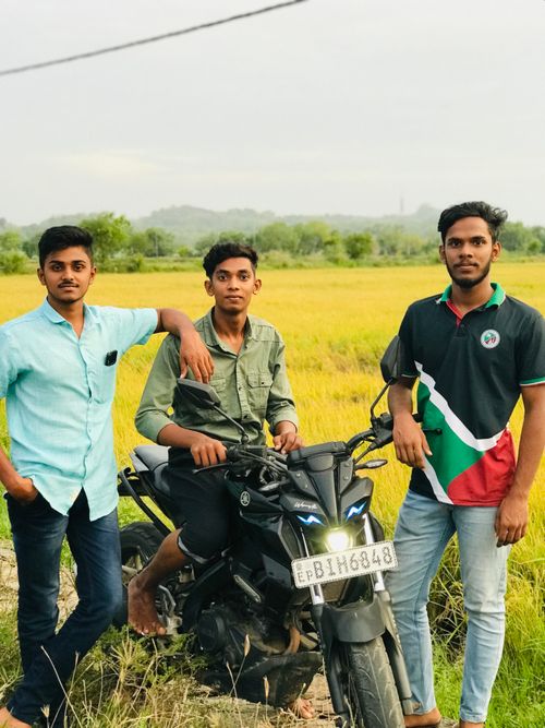 Free Three young men enjoying their time outdoors with a motorcycle in a rural setting. Stock Photo