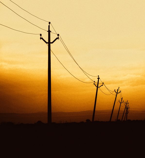 Majestic power lines silhouetted against a golden sunset sky in rural Kadapa, India.