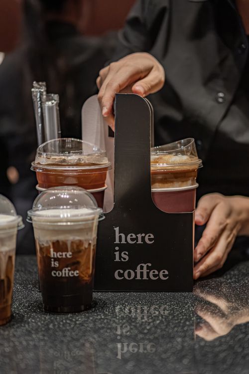 Free Close-up of hands serving iced coffee in takeaway carrier at a cafe. Stock Photo