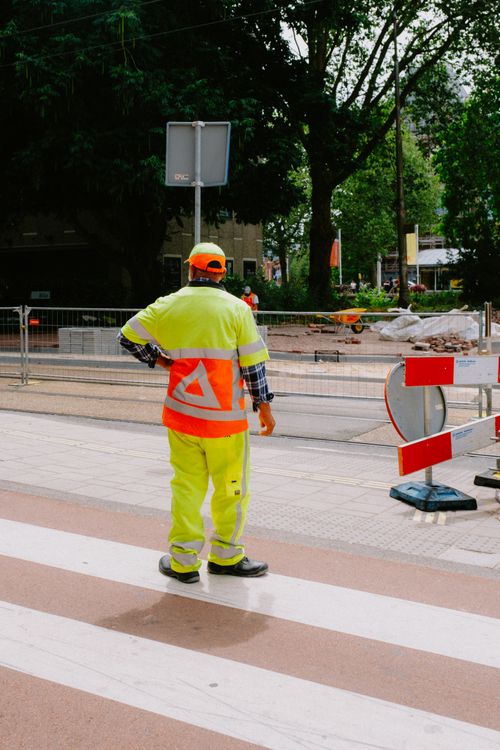 A man in a yellow safety vest standing on a street · Free Stock Photo