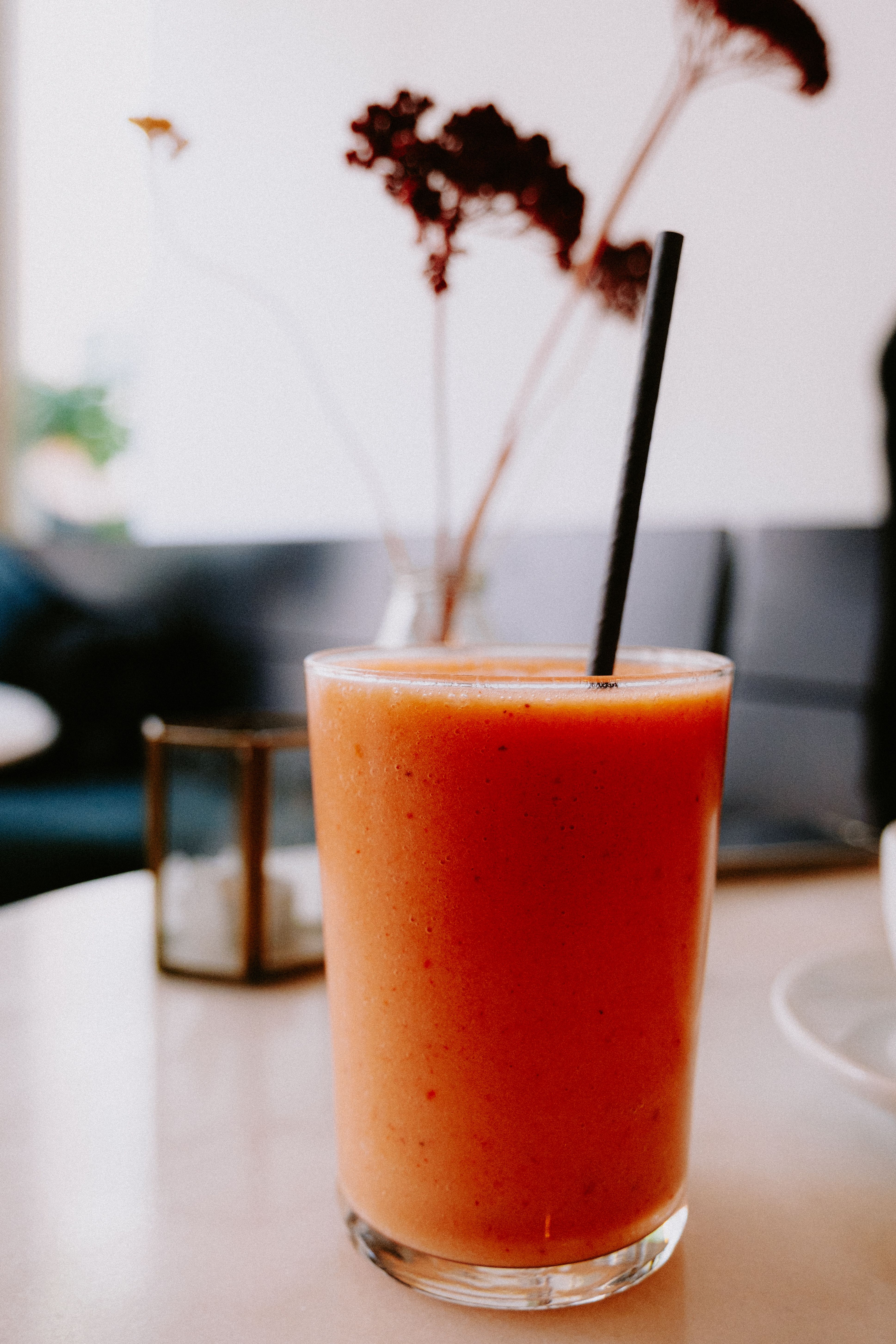 A vibrant tropical smoothie in a glass on a sunny cafe table.