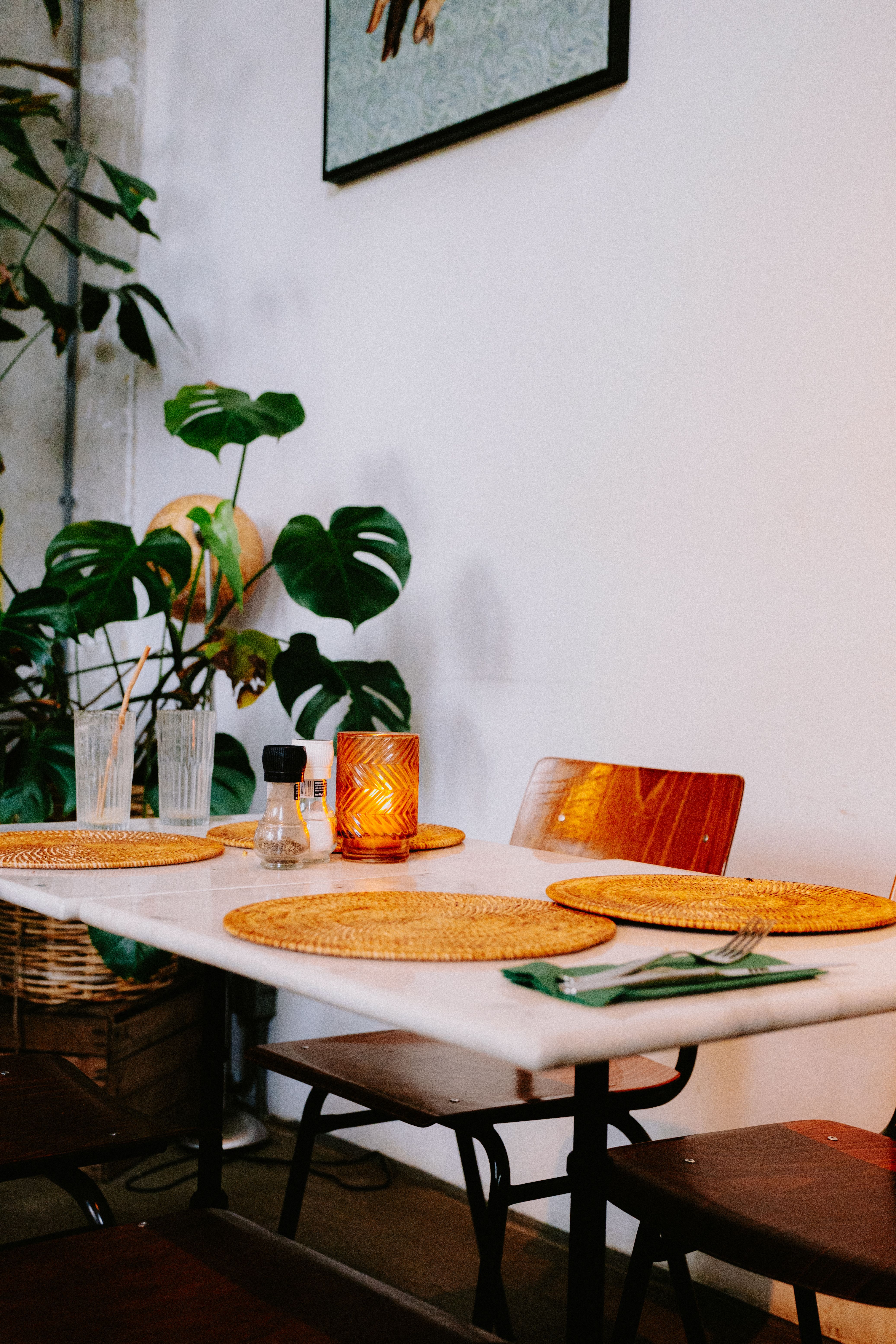 Stylish modern dining area with wooden chairs, plants, and elegant tableware.