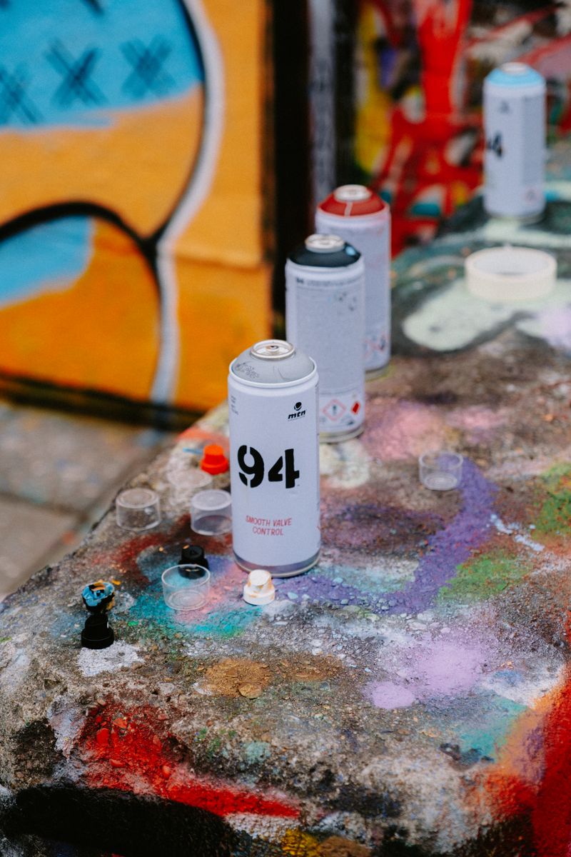 Assortment of spray paint cans lined up on a workshop table next to cut stencils