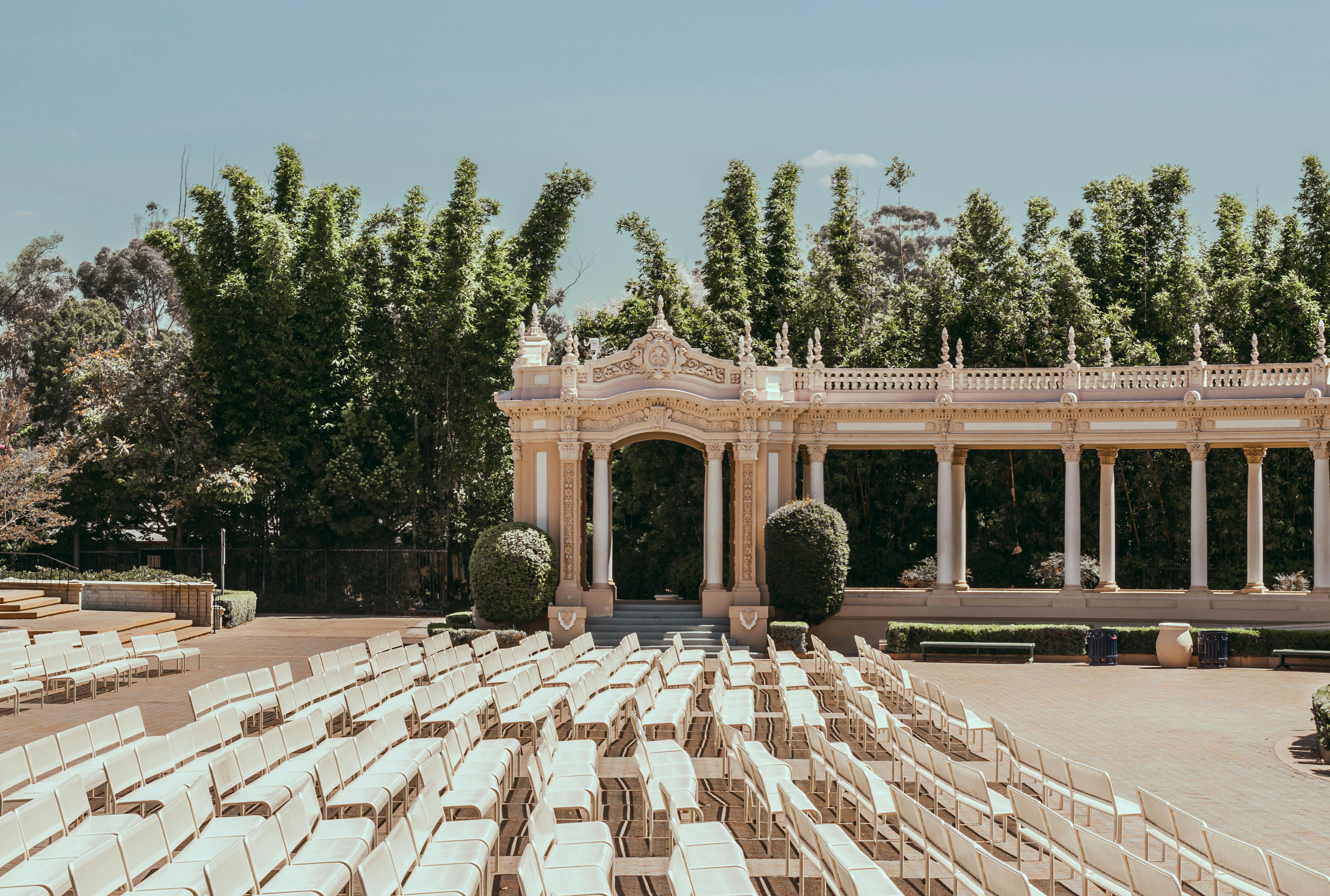 Free Elegant outdoor theater with rows of white chairs in San Diego's lush green surroundings. Stock Photo